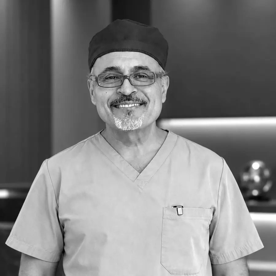 Dr. Kevin Tehrani smiling in light scrubs and a surgical cap
