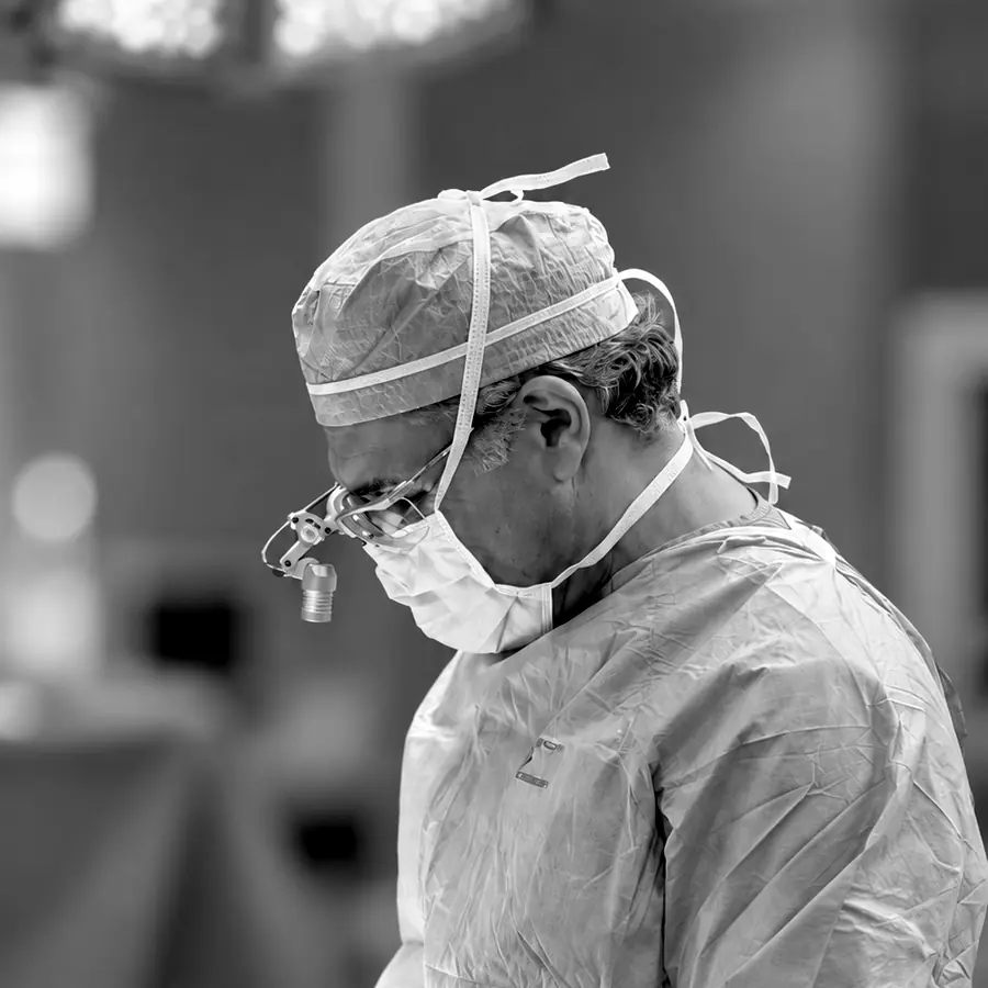 Dr. Kevin Tehrani in surgery, wearing a cap, mask and surgical loupes